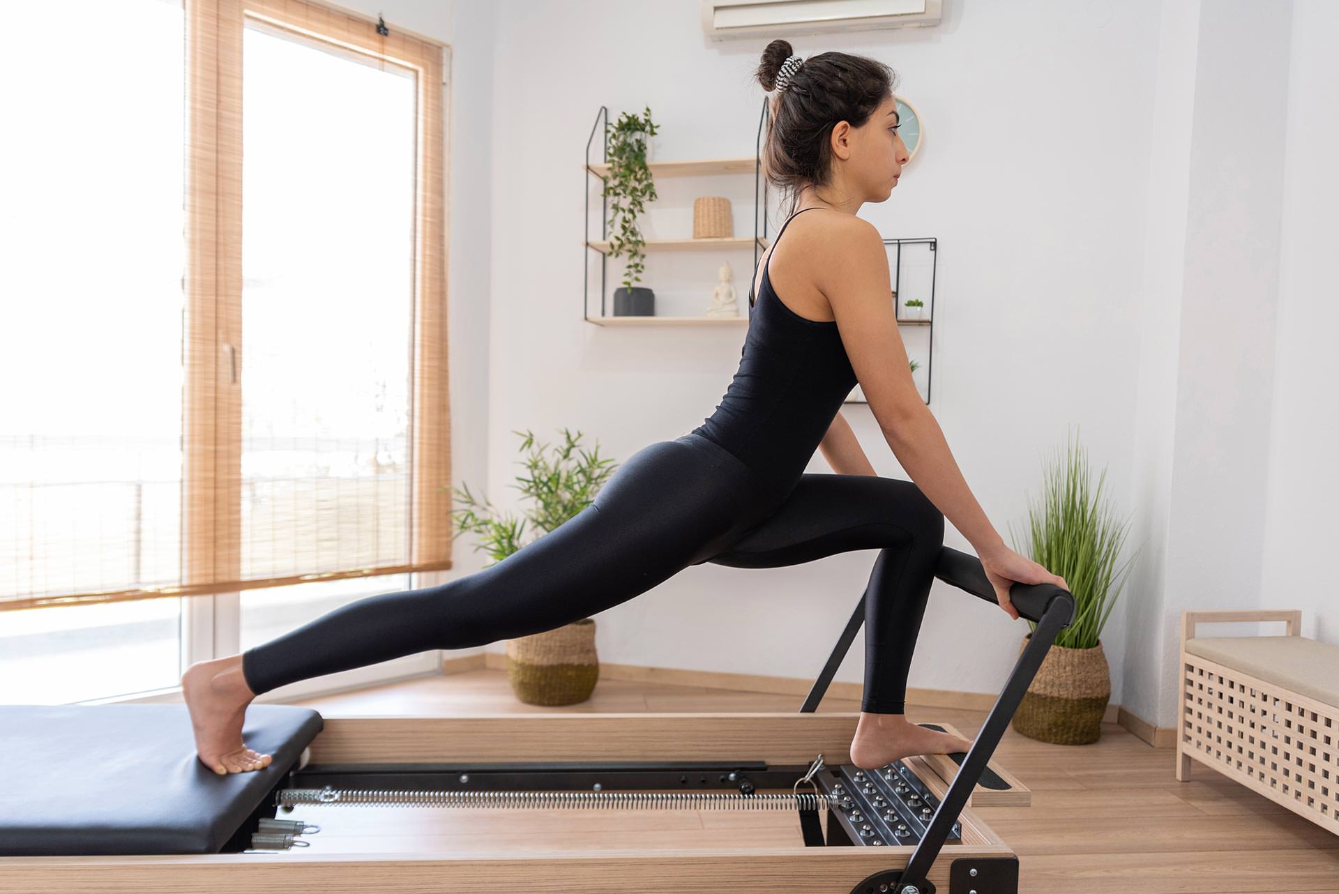 young woman exercising on pilates reformer bed